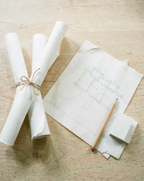Rouleaux de plans, calque et crayon sur un bureau en chêne