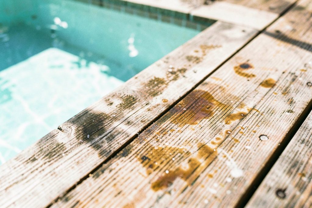 Weathered teak decking beside turquoise pool showing grain and salt patina
