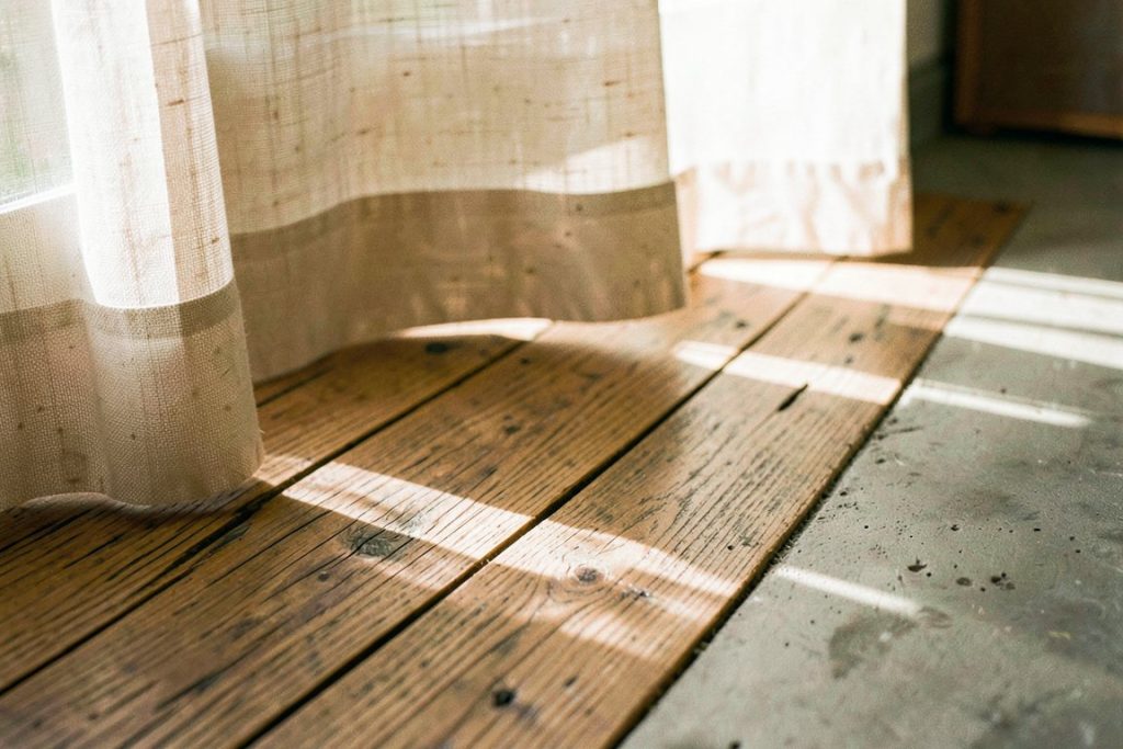 Weathered oak flooring meeting raw concrete under warm afternoon light